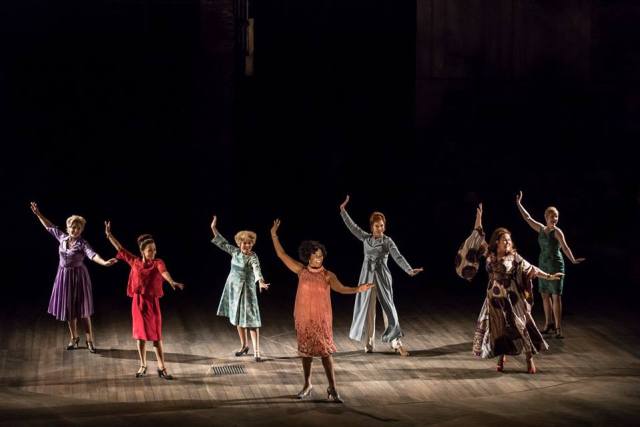 Photo by Johan Persson. Seven of the old Follies tap dance in formation. Arms in the air, toes pointed out. 