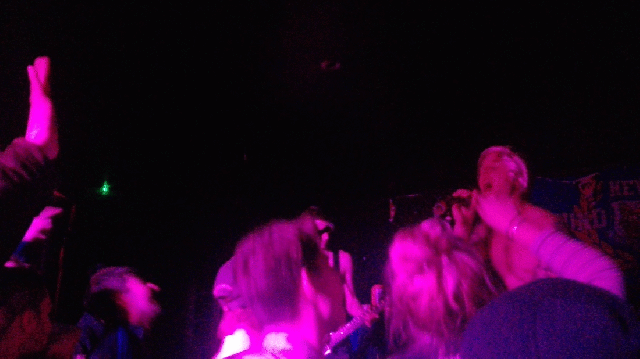 10 frame gif of a jumping crowd lit in purple in front of a band. front man shirtless in a blonde wig as costume. The Royals are pretending to be Red Hot Chili Peppers. 
