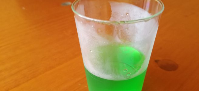 small neon green drink in a plastic cup.