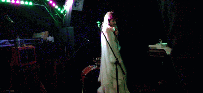 gif of vanity fairy stepping to the side under flashing green and purple lights. she rotates to make the skirt flare out