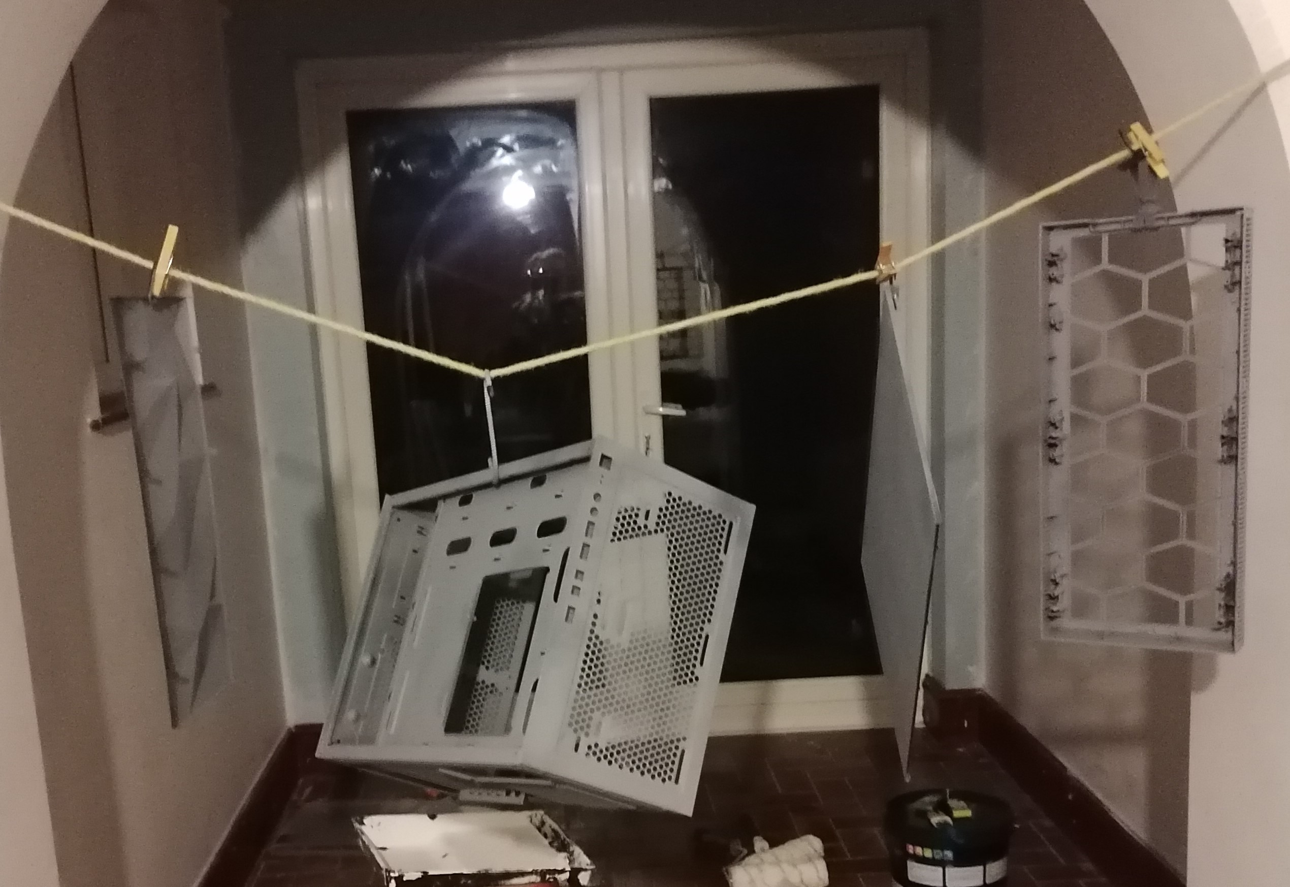 Parts of the PC case hanging up to dry on a rope hung accross a room above a drop cloth.