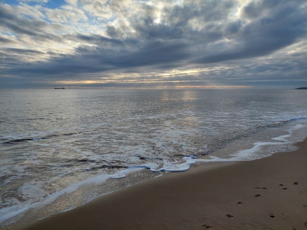 moody photo of sea with dark clouds and light shining through